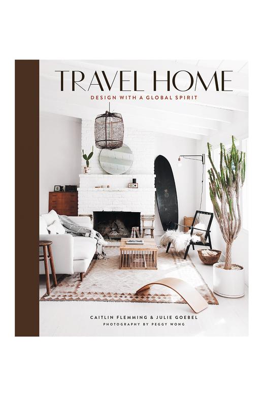 The TRAVEL HOME: DESIGN WITH A GLOBAL SPIRIT by Books features a white living room with a fireplace, showcasing elegant design and interiors.
