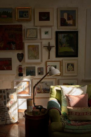 A Victoria Alexander home with paintings on the wall and a green couch.