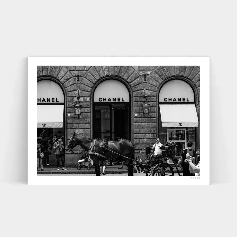 A black and white photo of a horse drawn carriage in front of a Chanel store, captured in timeless frames by the Fashionably Late Art Prints service.