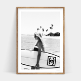 A black and white photo of a woman holding a surfboard, Surfer Chic by Art Prints, available for prints.