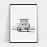 A black and white photo of a lifeguard tower on the beach available for Number 5 Art Prints and delivery.