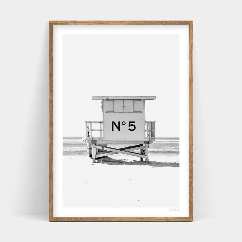 A black and white photo of a lifeguard tower on the beach, Number 5 Art Prints, available for delivery.
