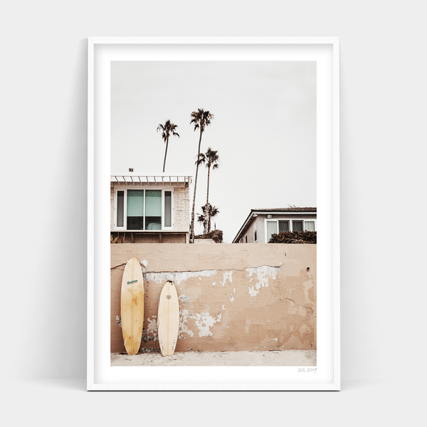 Two Beachfront surfboards leaning against a wall, ready for delivery.