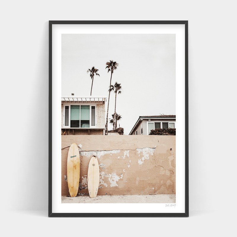 Two Beachfront surfboards leaning against a wall, available for delivery (by Art Prints).