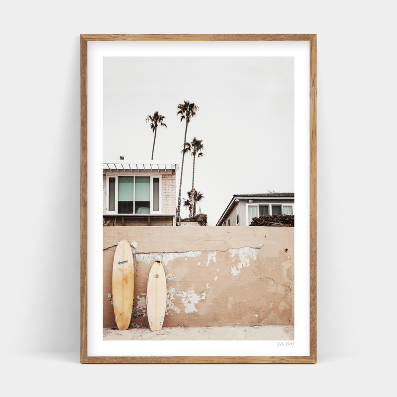 Two Beachfront surfboards leaning against a wall, available for delivery. (Brand name: Art Prints)