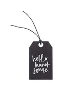 An Emma Kate Co black gift tag with the words 'hello handsome' on it, attached to hemp twine.