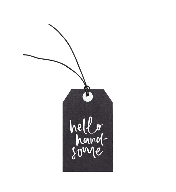 An Emma Kate Co black gift tag with the words 'hello handsome' on it, attached to hemp twine.