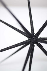 A close up of a small Christmas '23 Black Sphere umbrella on a white surface.