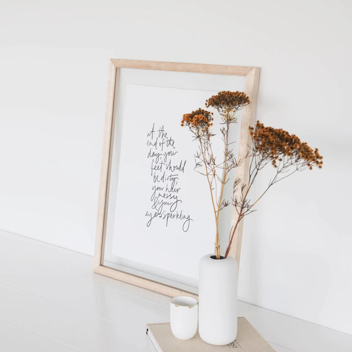 An eco-friendly AXEL & ASH Eyes Sparkling Print with a quote on recycled cotton rag paper, displayed alongside a vase of flowers.