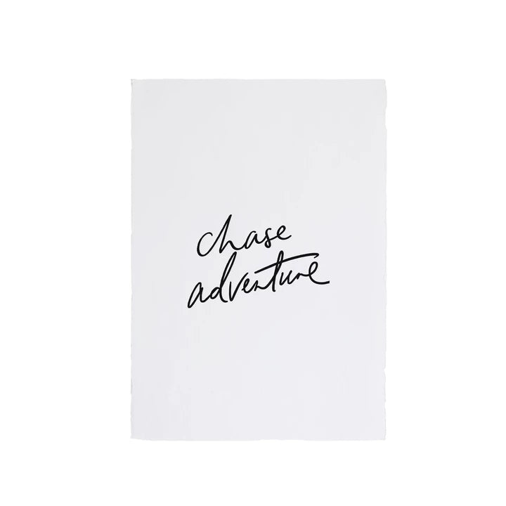 A white piece of paper with the words 'Chase Adventure' and art prints on it, showcasing AXEL & ASH's eco-friendly range for the wanderlust-spirit.