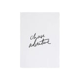 A white piece of paper with the words 'Chase Adventure' and art prints on it, showcasing AXEL & ASH's eco-friendly range for the wanderlust-spirit.