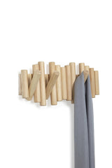 A wooden coat rack with a Picket Rail Five Hooks by Umbra hanging on it, serving as both functional storage and wall art.