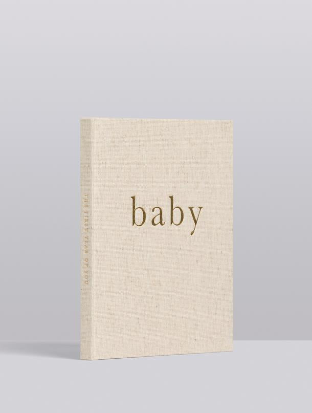 Oatmeal linen baby journal standing upright, angled view of the cover and spine
