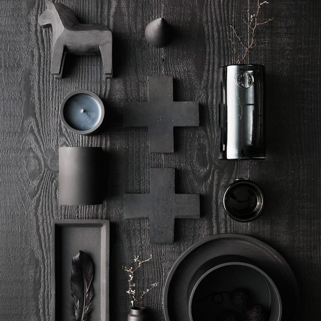 Charcoal concrete trays, dishes and candle holders arranged on dark timber
