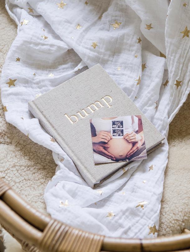 Bump pregnancy journal with a baby photo in a rattan basket lined with a star-print muslin