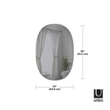 An Umbra Hub Mirror - Bevy Oval 24X36 - Smoke with a copper finish, featuring a curtain and a window.
