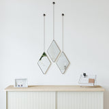 Three Dima Mirrors hanging above a white dresser, produced by Umbra.