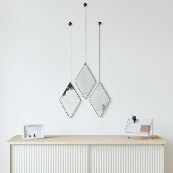 Three Dima Mirrors hanging above a white dresser, produced by Umbra.