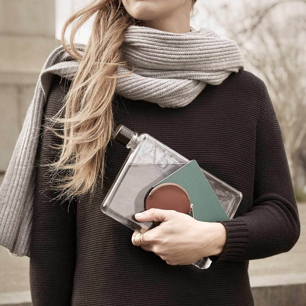 A woman carrying a clear clutch while holding an A5 Memobottle from MemoBottle.