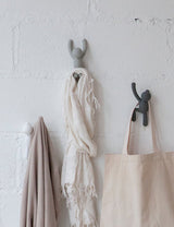 A durable molded polypropylene tote bag hanging on a Buddy Hooks - Set of 3 Multi Grey attached to a white wall from the Umbra brand.