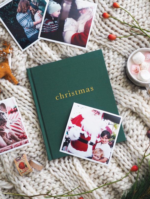 Forest green linen Christmas family book on a knitted throw among family photographs