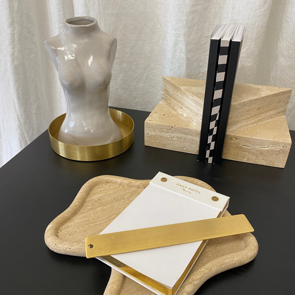 A Papier HQ TRAVERTINE CURVED TRAY with a book and a notepad on it, perfect for sustainability-conscious customers.