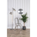 A striped wall with a metal chair and a plant, adorned with a Karlsson Distinct Wall Clock - Silver.