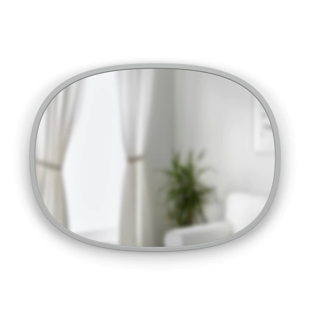Grey Hub oval mirror hung landscape, reflecting curtains and a plant