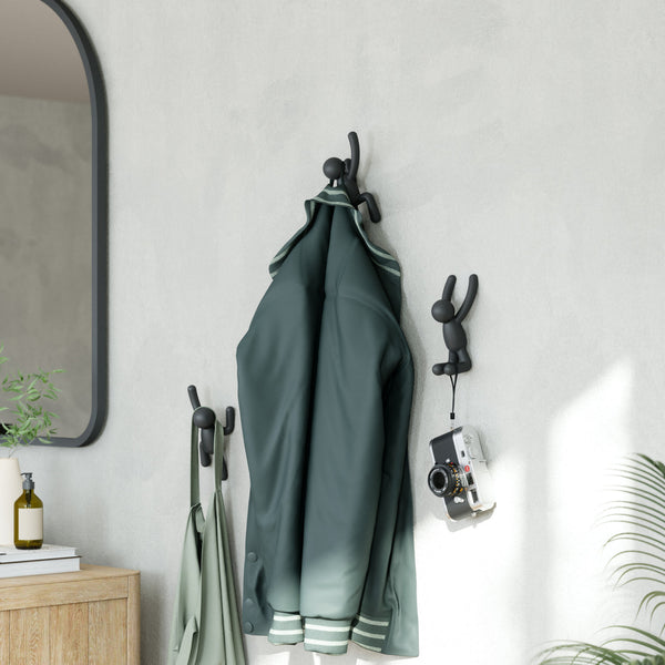 An Umbra Buddy Hooks Black - Set of 3 coat rack hangs on the wall next to a mirror.