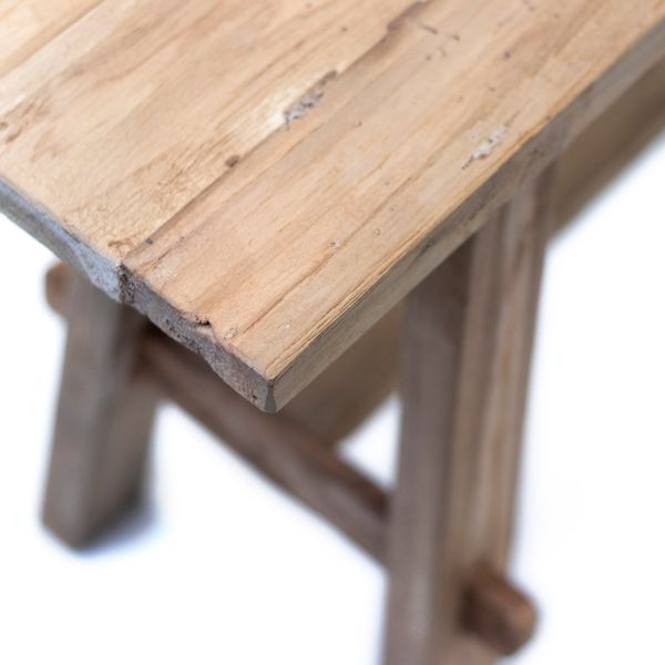 Close on the bench's teak top and leg joint, showing the grain and saw marks