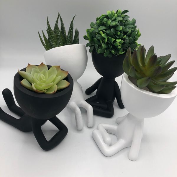 Egg head planters in black and white holding succulents and greenery