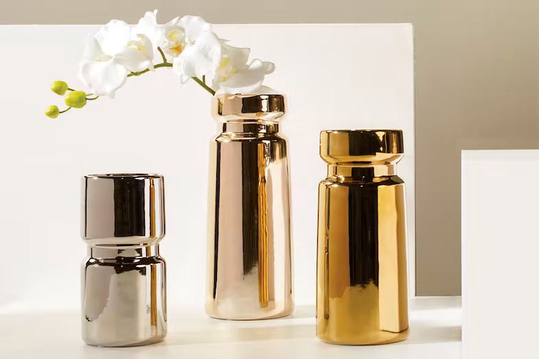 The cylinder vase in silver, rose gold and gold together beside a white orchid