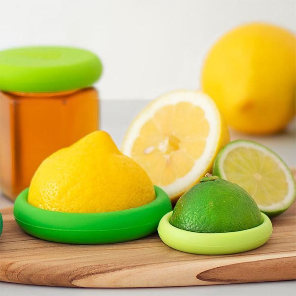 A cutting board with lemons, limes, and a Food Huggers Citrus (SET OF 2- CITRUS).