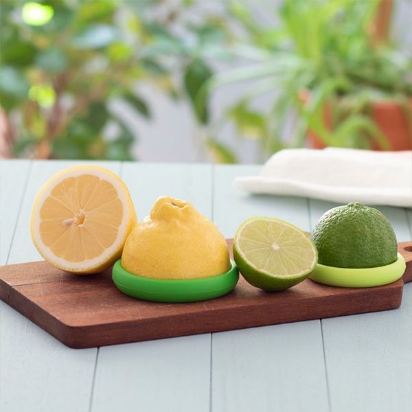 Three lemons on a wooden cutting board, ready to be stored with Food Huggers Citrus for freshness that lasts longer. Replace "Food Huggers Citrus" with "SET OF 2- CITRUS" from the brand name "Food Huggers".