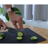 A person slicing cucumbers on a Dishy CHOPPING BOARD - Black.