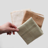 A hand holding a set of three NAWRAP ORGANIC MINI TOWELS - IVORY, made from natural materials and suitable for sensitive skin. (Brand: Flux Home)