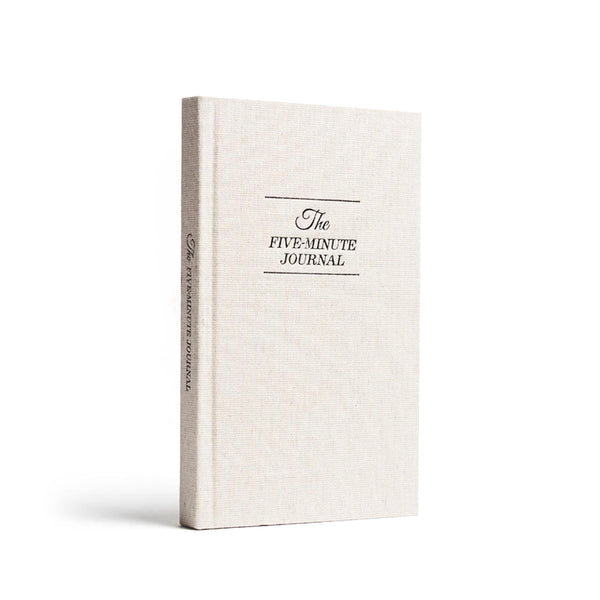 A white The Five Minute Journal with a black cover on a white background by Intelligent Change, promoting self-help and positivity.