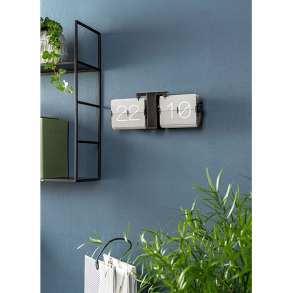 A Karlsson Flip Clock - Grey with a plant on it.