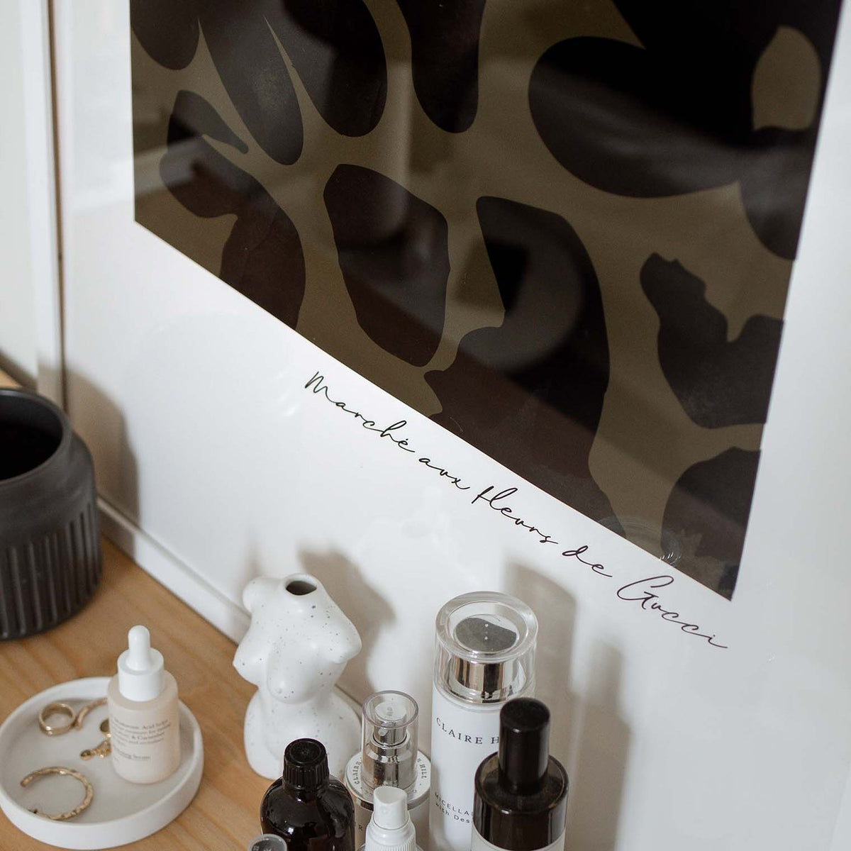 Close view of the framed Flower Market print above perfume bottles and a tray