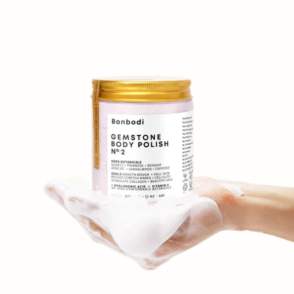 A hand holding a jar of Bonbodi Gemstone Body Polish - Quartz Micro Crystals to reduce blemishes.