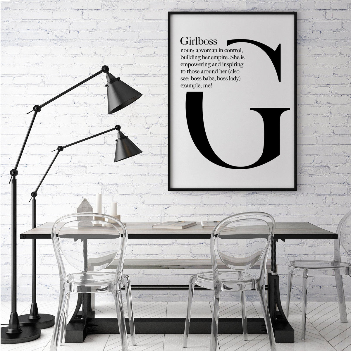 Girlboss print above a dining table with clear chairs and a black floor lamp