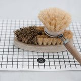 A Good Change eco cloth - large (2-pack) sits beneath a wooden brush, providing a sustainable cleaning solution.