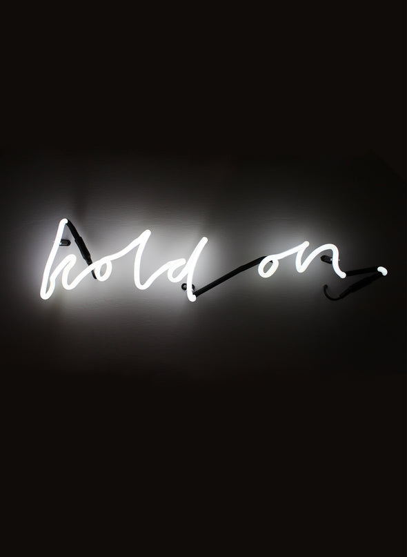 Hold On wall neon in white script, lit against a dark wall