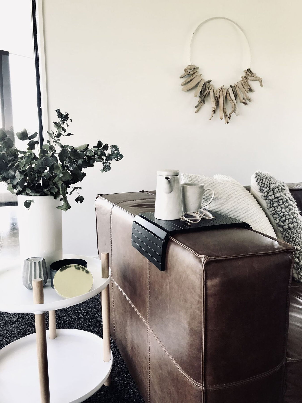 Ned Collections Arm Chair Side Rest on a brown leather sofa beside a coffee table