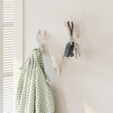 A Umbra Buddy Hooks White - Set of 3 wall décor featuring a white coat hanger with a checkered shirt.