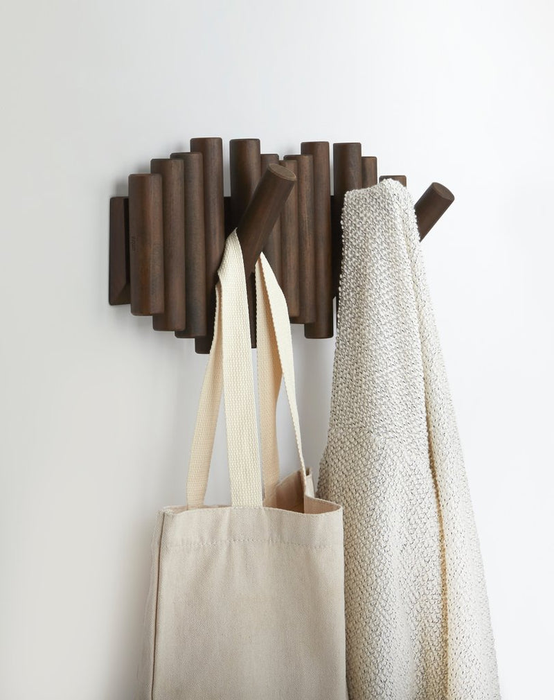 A stylish Picket Rail Wall Hook adorned with flip hooks from the Umbra range, serving both as a practical storage solution and wall art. The rack includes an additional touch of functionality with a tote bag.
