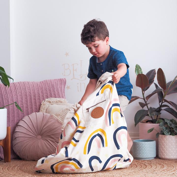 A young boy playing with a Play Pouch in a living room decorated with glow in the dark stars and the Rainbows & Stars Printed Play Pouch.