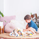 A young boy playing with a Rainbows & Stars Printed Play Pouch in a room decorated with glow in the dark stars.
