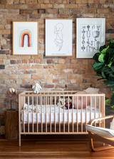 A contemporary interior featuring a stylishly decorated baby's room with a crib, a rocking chair, and framed pictures from Our Spaces - Contemporary New Zealand Interiors by Books.