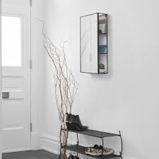 Umbra Cubiko mirror and storage unit in black in an entryway with shoes and branches